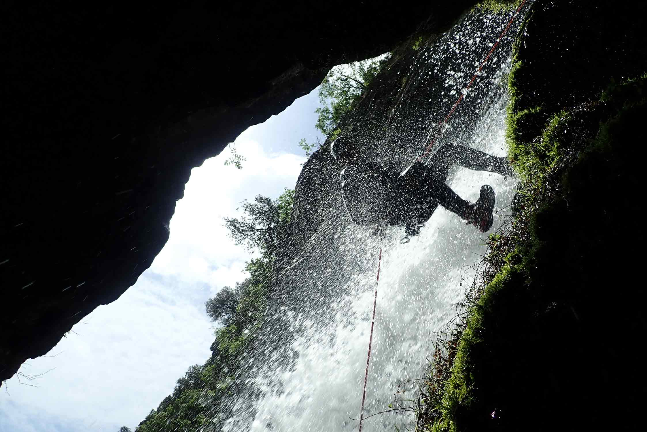 Un aventurier audacieux en rappel dans un canyon entouré de cascades étincelantes.