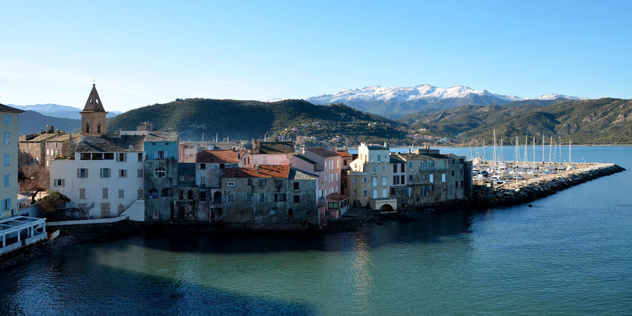 Vue spectaculaire du port de Saint-Florent en Corse avec ses maisons colorées, montagnes grandioses et mer paisible