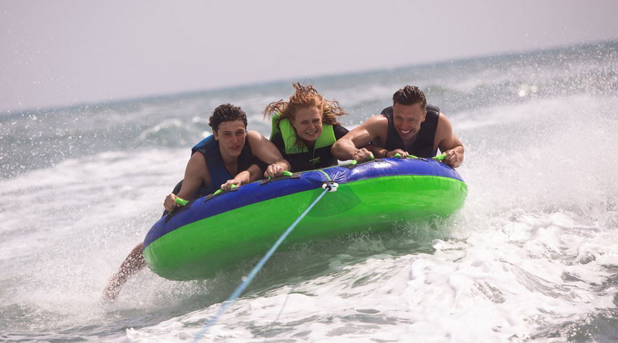 Aventures nautiques en famille à la plage Plage estivale où des amis s'amusent sur une bouée tractée, capturant l'excitation et l'adrénaline des activités aquatiques.