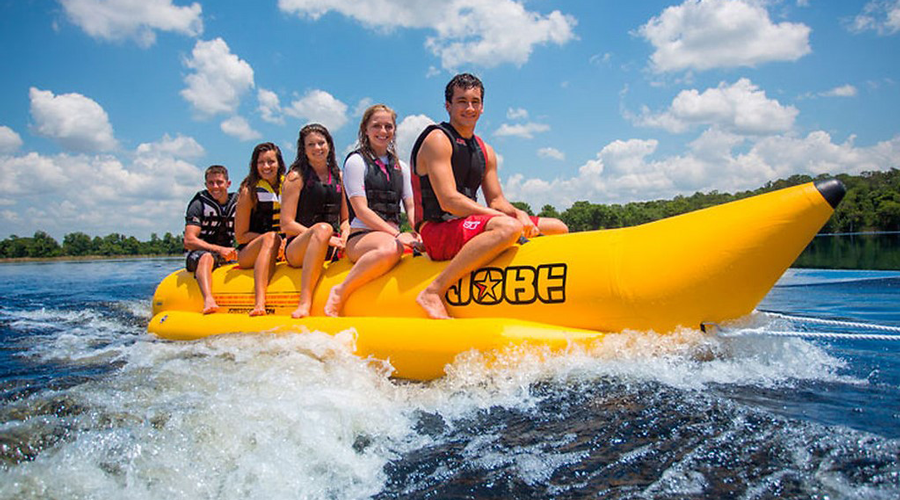Aventure en bouée jaune sur l'eau sous le ciel bleu Activités estivales sur un lac : amis sur une bouée jaune sous un ciel ensoleillé.