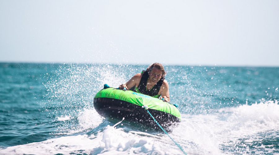 Sport nautique d'été et sensations fortes Homme sur une bouée tractée, éclaboussures d'eau, ambiance excitante