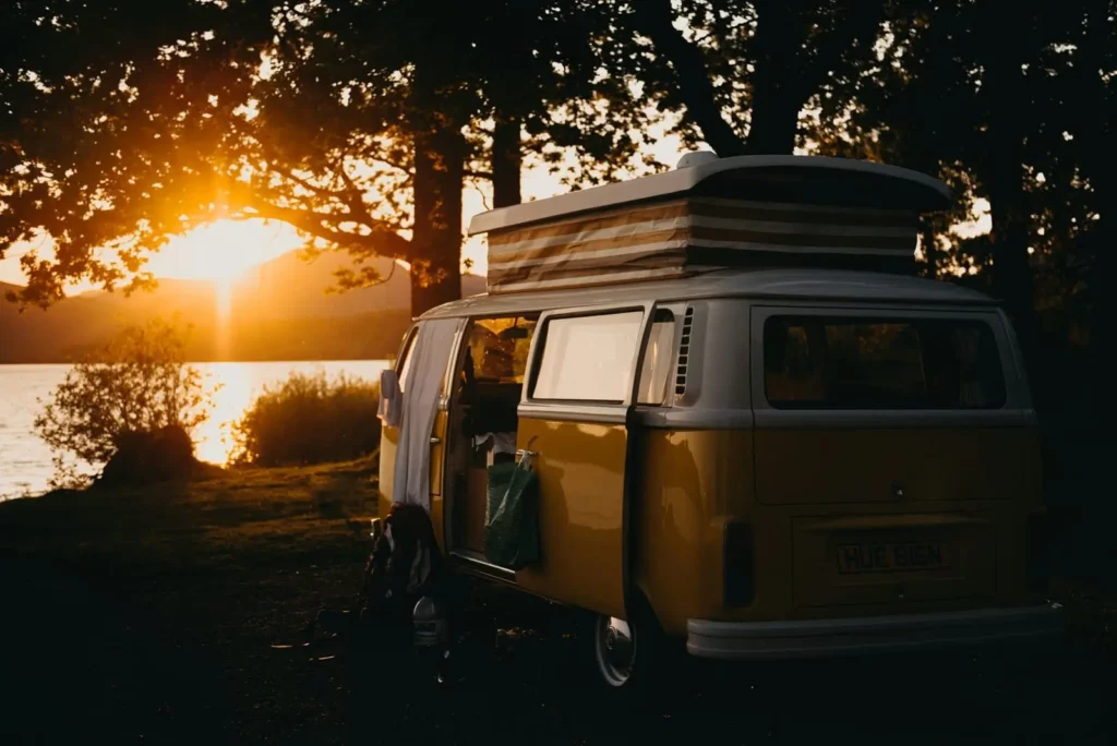 Campervan KevinSchmid entête formule étape Van aménagé stationné au bord de l’eau au coucher du soleil, esprit camping nature et vacances nomades