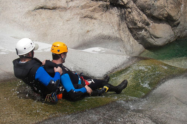 Deux aventuriers s'immergent dans la nature pour une séance de canyoning pleine d'adrénaline, au milieu de formations rocheuses et d'eau claire sous le soleil.