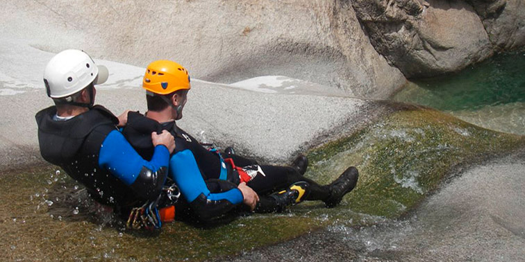 Image captivante de deux aventuriers engagés dans une descente exaltante le long d'une rivière torrentueuse, avec des combinaisons et casques de sécurité, mettant en avant le frisson et la puissance des eaux vives en canyoning.