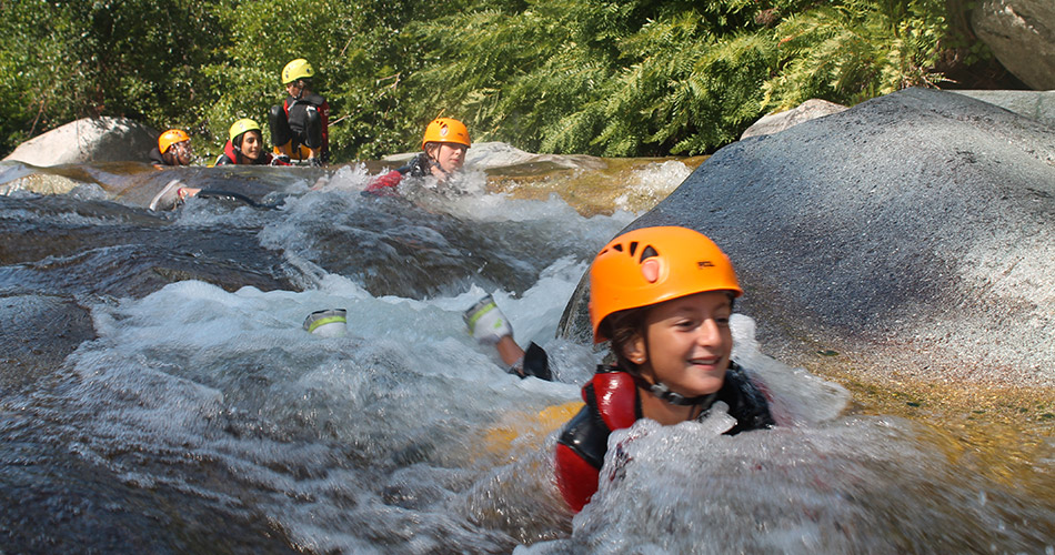 Aventure aquatique en pleine nature avec des enfants Image d'enfants s'amusant lors d'une aventure aquatique, portant des casques pour la sécurité tout en glissant sur des eaux vives sous le soleil, dans un décor naturel luxuriant et apaisant, renforçant le lien avec la nature.