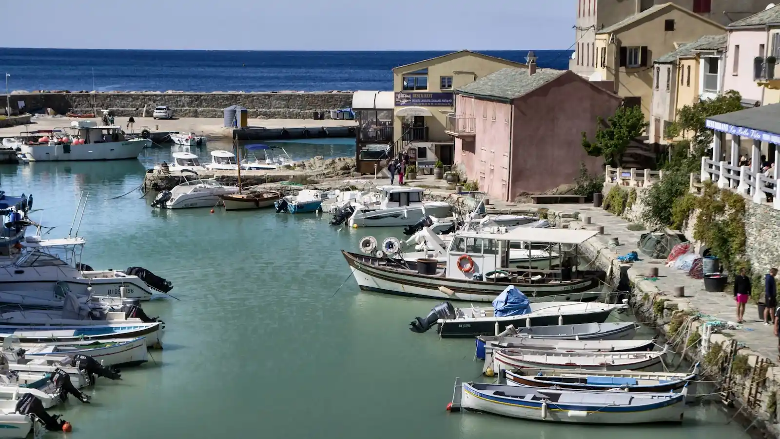 Barques de pêcheurs et pointus amarrés dans le port de Centuri au pied des maisons traditionnelles de Haute-Corse.