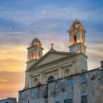 Façade de l'église Saint-Jean-Baptiste dominant le Vieux-Port de Bastia au coucher du soleil.