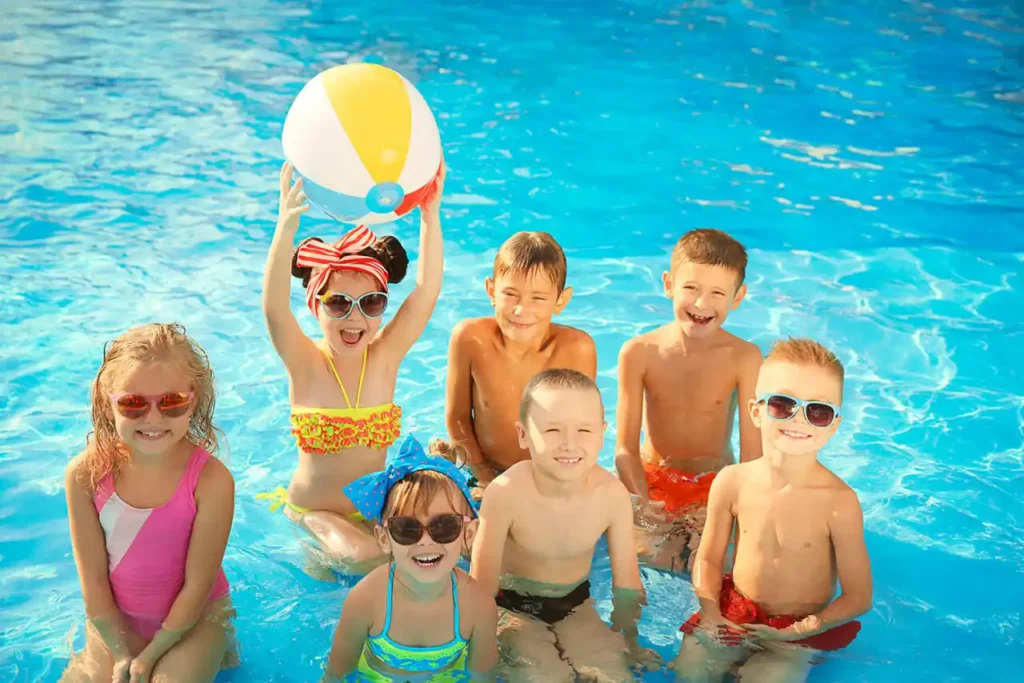 Groupe d'enfants souriants jouant avec un ballon dans la piscine d'un camping avec animations en Haute-Corse.