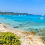 Eaux turquoise et sable blanc de la plage du Lotu avec des bateaux au mouillage, Haute-Corse.