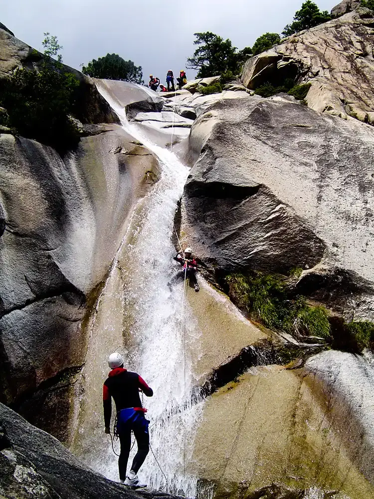 Sportif descendant une grande cascade naturelle en rappel lors d'une sortie canyoning avec Alpa Corse en Corse.