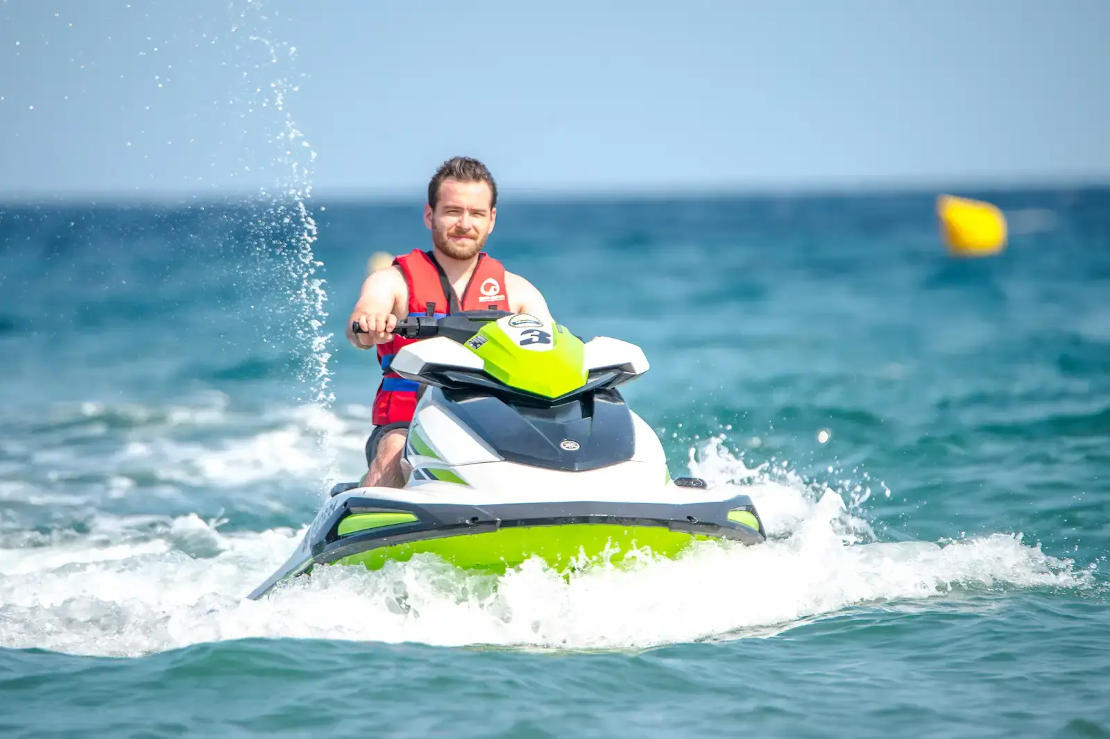 Homme souriant pilotant un jet ski Yamaha blanc et vert sur les eaux turquoise de la Méditerranée en Corse.
