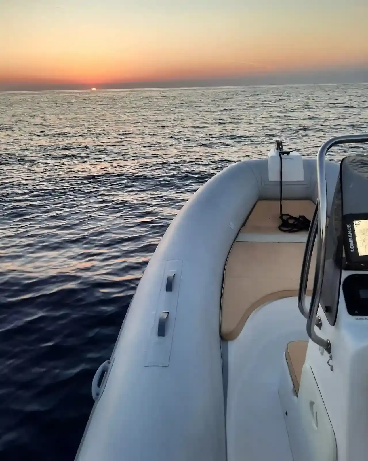 Vue depuis la proue d'un bateau pneumatique sur l'horizon au coucher du soleil dans la réserve naturelle de Scandola, Corse.