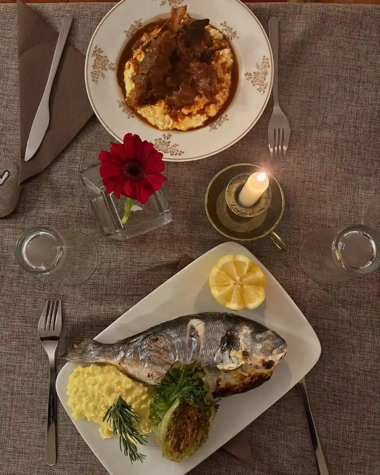 Table de restaurant avec une daurade grillée au romarin et un plat de viande braisée, le choix du meilleur restaurant à Moriani Plage.