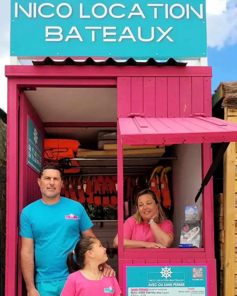 L'équipe de Nico Location devant leur kiosque rose à Galéria, proposant la location de bateaux avec ou sans permis.