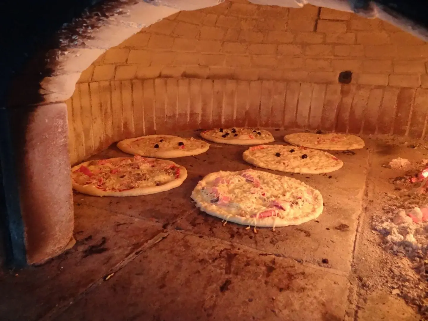 Préparation de pizzas traditionnelles cuites au feu de bois dans le restaurant du camping A Stella.