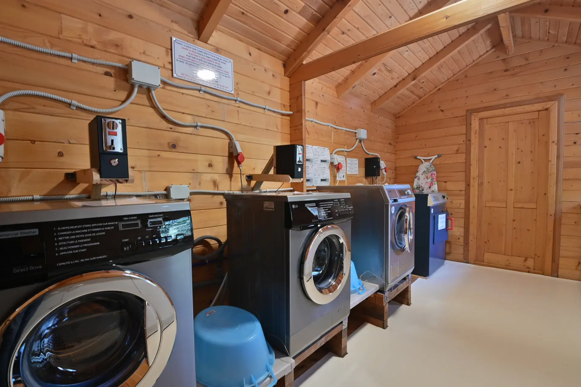 Espace laverie propre et moderne avec machines à laver frontales et sèches-linge pour les vacanciers.