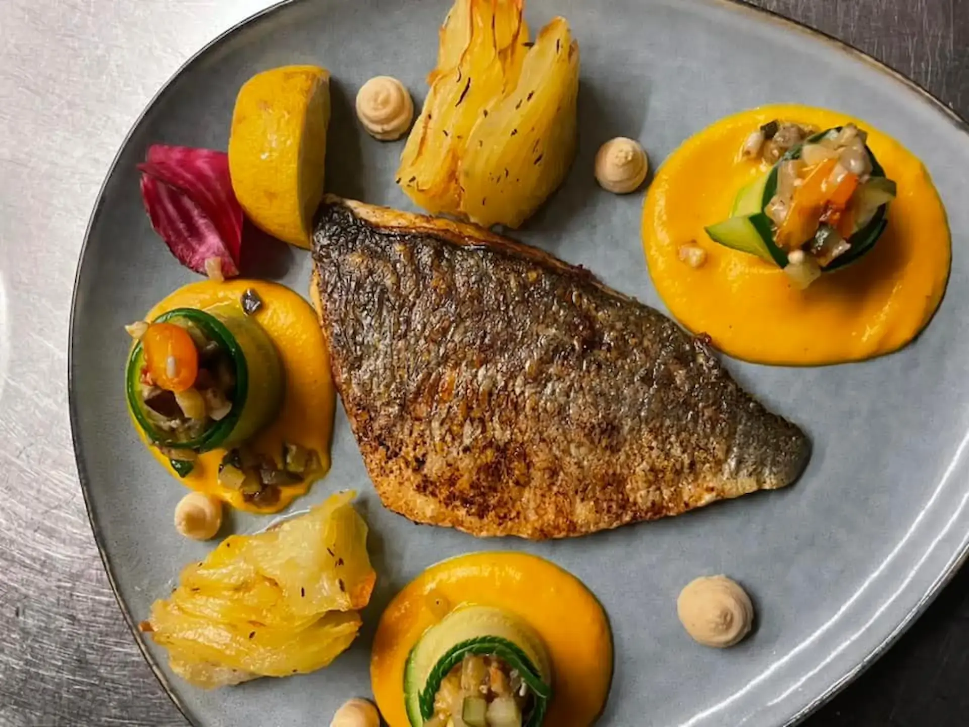 Filet de poisson local grillé avec sa peau croustillante, purée de légumes de saison et petits légumes croquants, une création du meilleur restaurant traditionnel Corse.