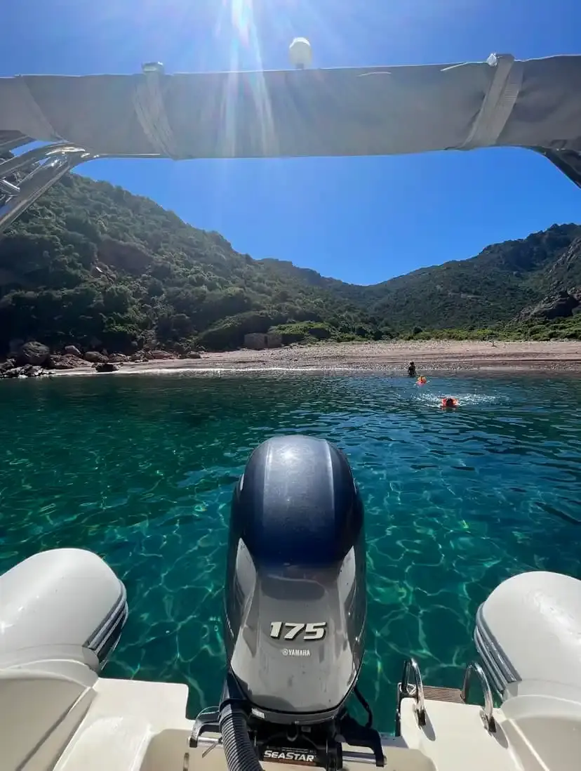 Vue depuis l'arrière d'un bateau avec moteur Yamaha 175 chevaux arrivant sur une plage sauvage en Corse avec des baigneurs.