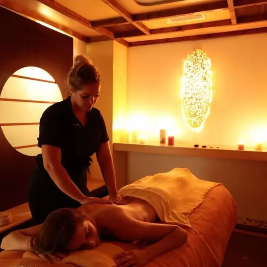 Cliente recevant un massage du dos dans une salle à l'ambiance chaleureuse avec éclairage tamisé et décor boisé.