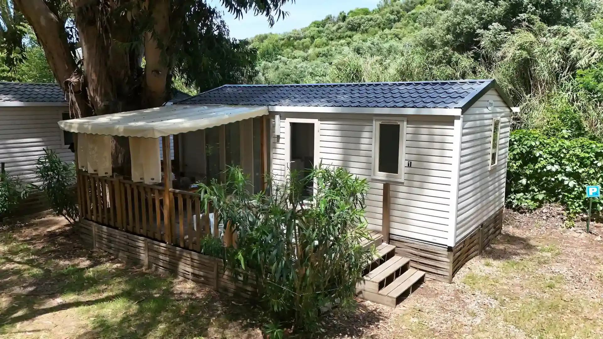 Mobil-home moderne avec terrasse en bois ombragée et salon de jardin privatif.