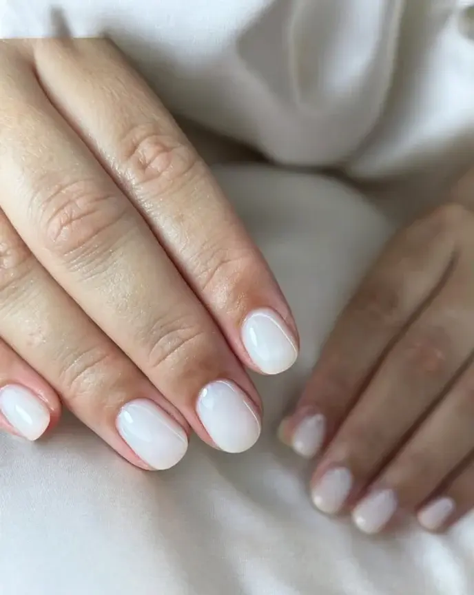 Pose de vernis semi-permanent blanc laiteux effet "milky nails" sur ongles courts pour une mariée.