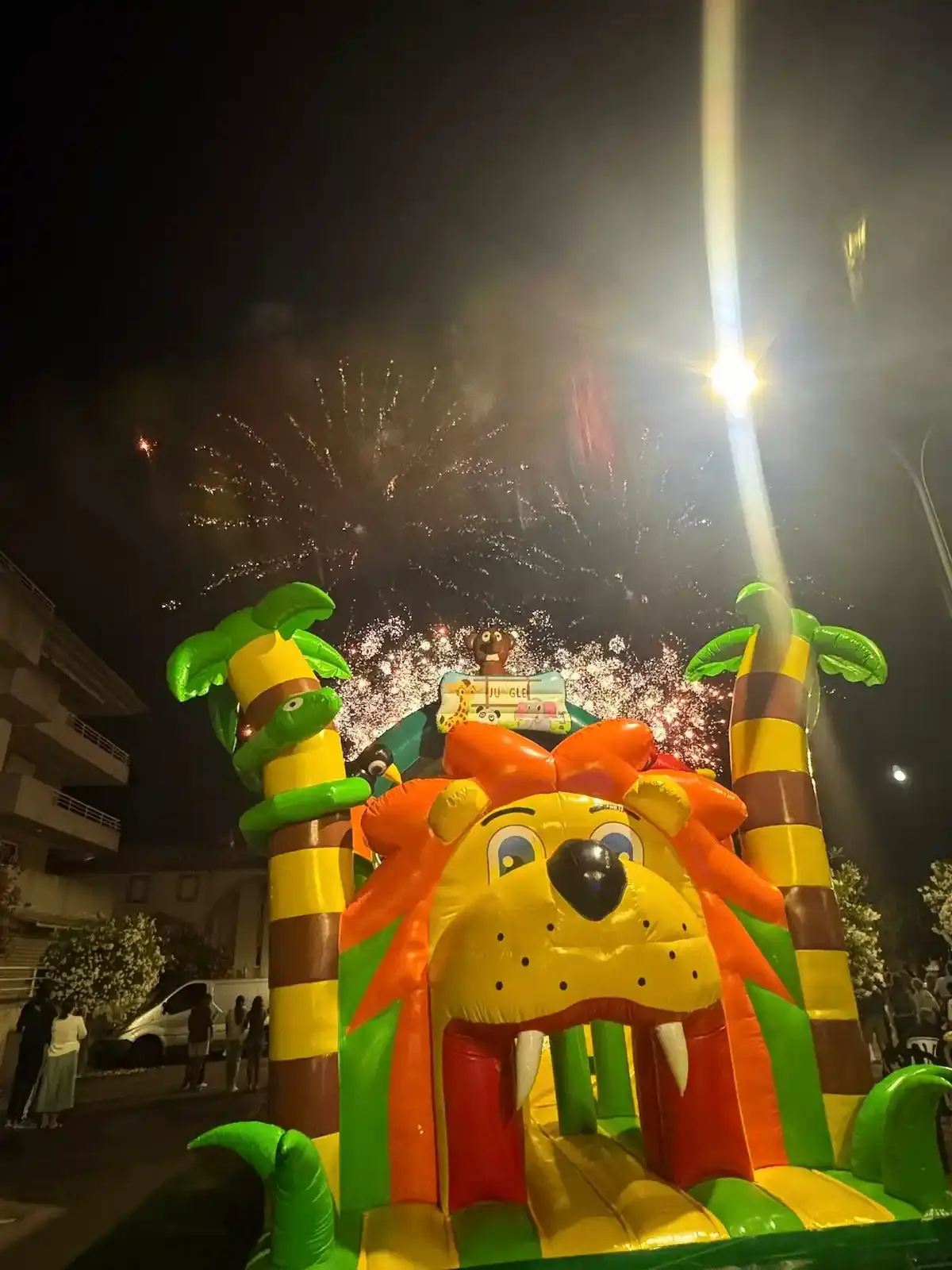 Château gonflable géant en forme de lion éclairé de nuit sous un feu d'artifice lors d'un événement en Corse.