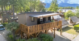 Chalet en bois sur pilotis avec large terrasse surélevée offrant une vue sur les montagnes corses.