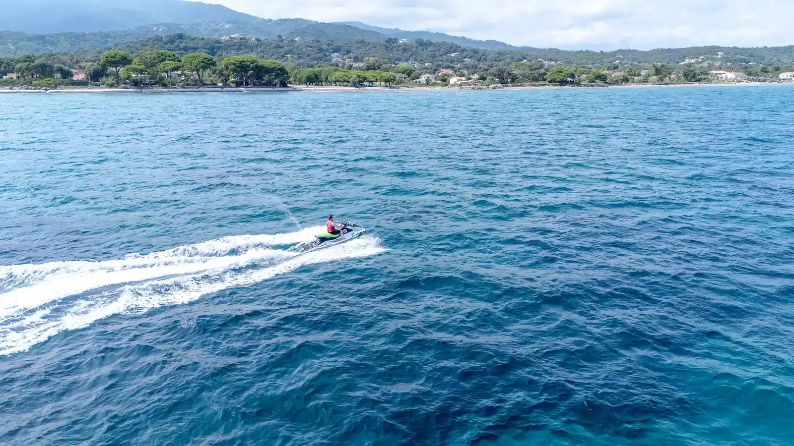 Pilote de scooter des mers naviguant le long des côtes boisées de la Corse.