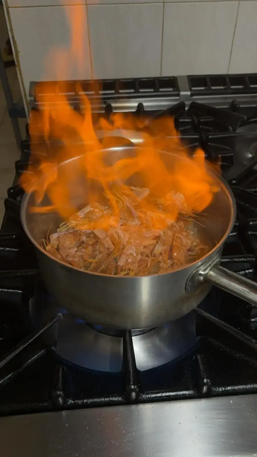 Chef cuisinier flambant des crustacés dans une casserole au restaurant U Lampione en Haute-Corse.