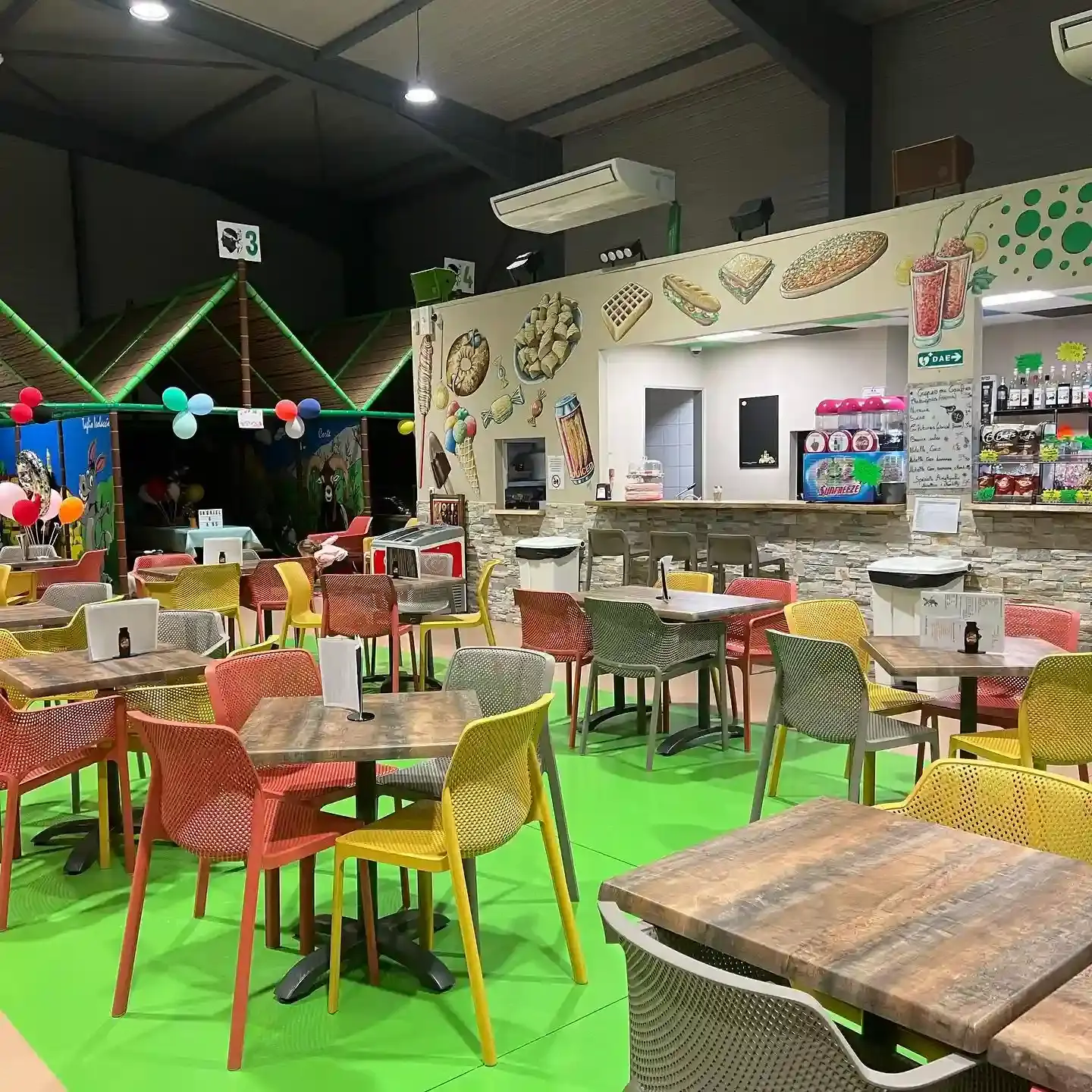Salle de réception moderne avec chaises colorées et comptoir snack décoré d'illustrations de gaufres et boissons.