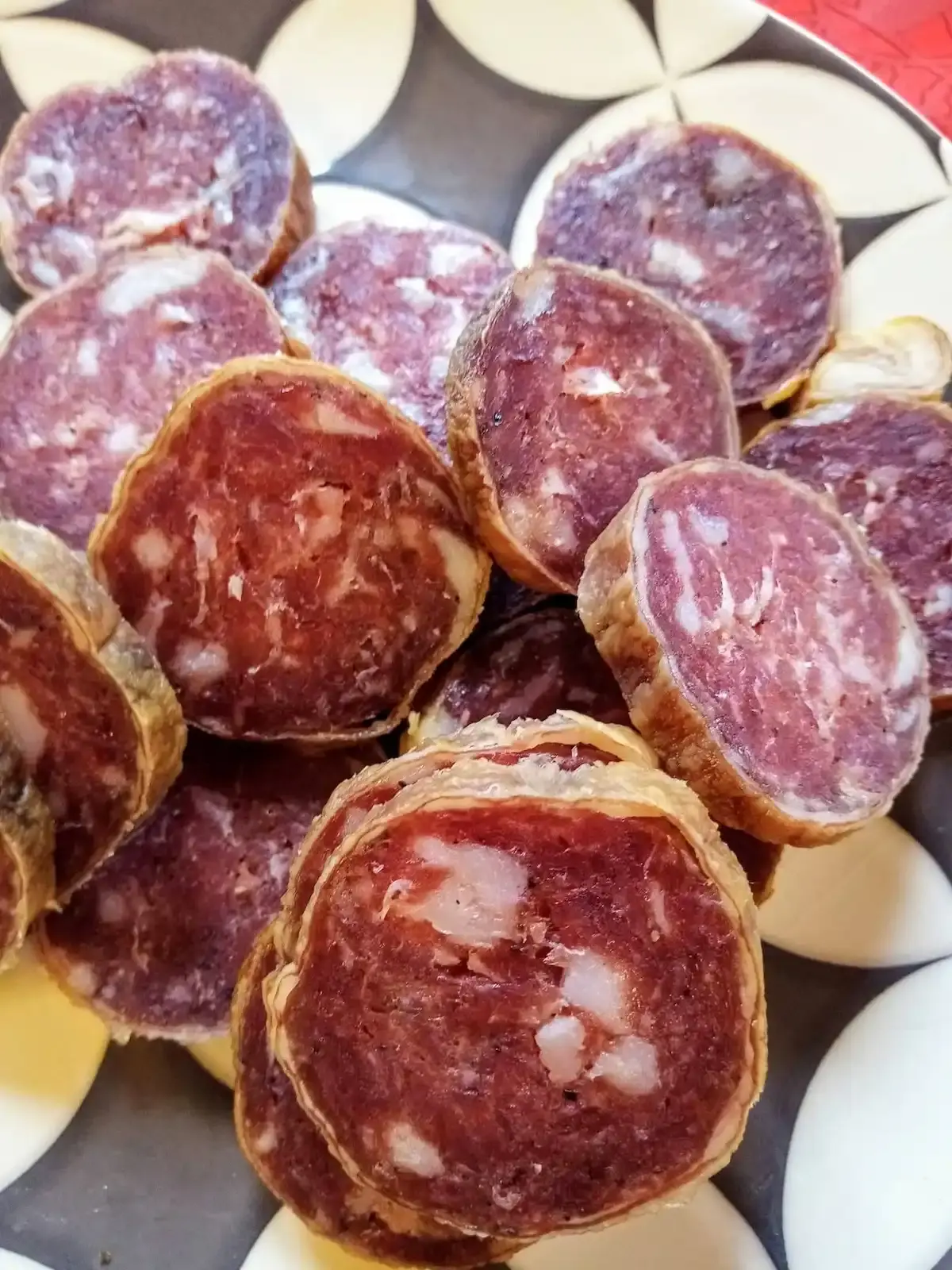 Une assiette ornée de tranches de saucisson corse artisanal, prêtes pour la dégustation à la charcuterie Gozzi.