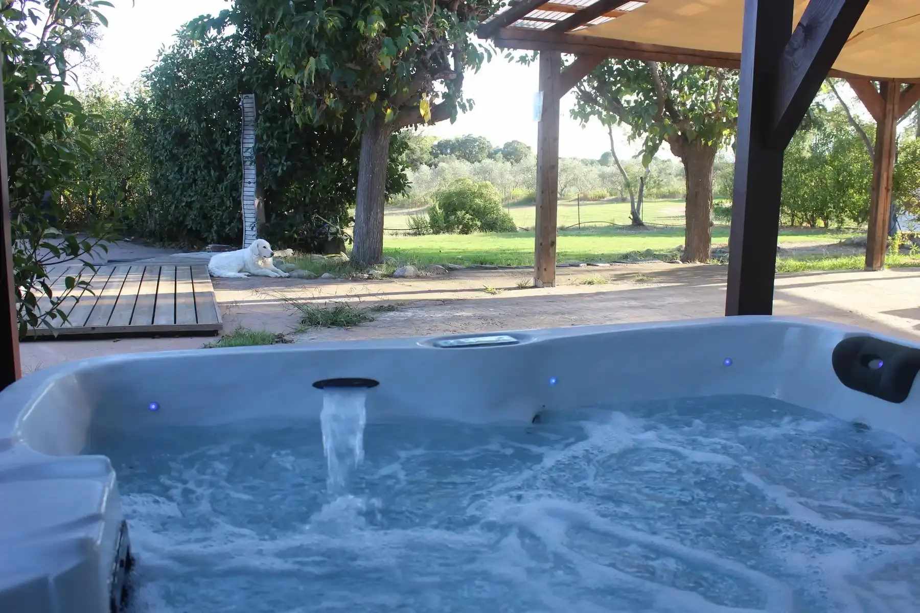 Spa jacuzzi extérieur bouillonnant sur la terrasse de la Villa A Sulana avec vue sur le parc arboré.