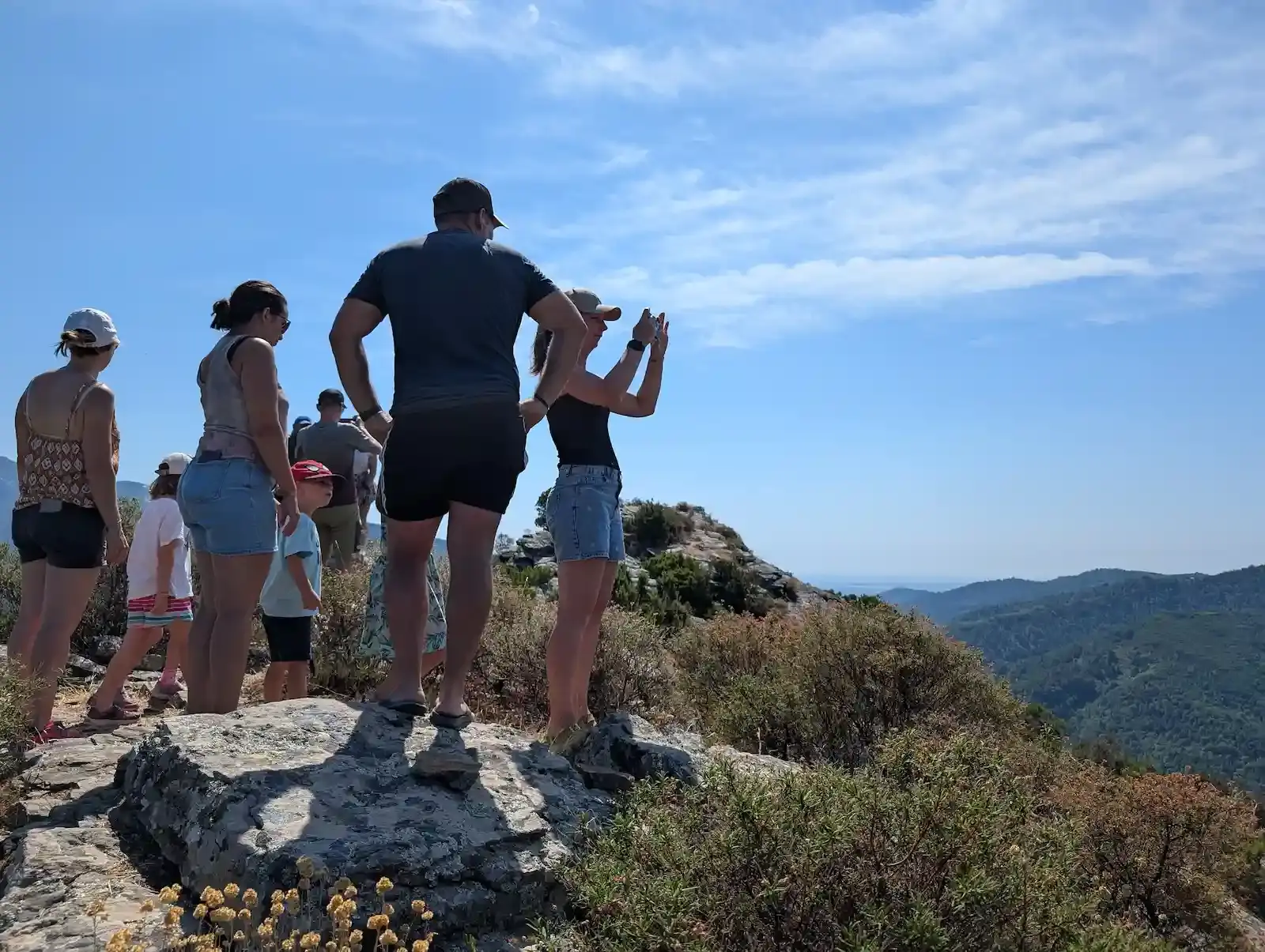 Un groupe de randonneurs profite de la vue spectaculaire sur les montagnes corses depuis une crête, illustrant le terroir d'altitude de la charcuterie Gozzi.