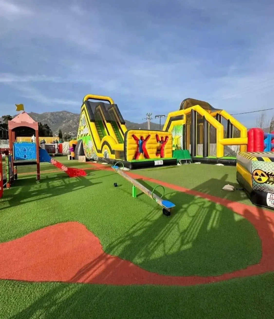 Vue d'ensemble de l'aire de jeux gonflables du Family Parc avec toboggans géants et parcours d'obstacles sur gazon synthétique en Corse.