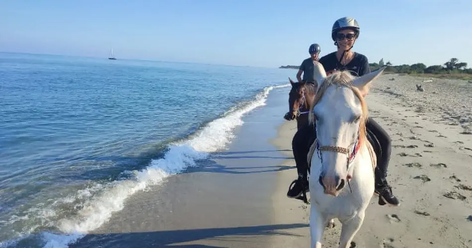 Cavaliers galopant sur le sable fin au bord de l'eau lors d'une balade à cheval sur la plage à San Giuliano en Corse.