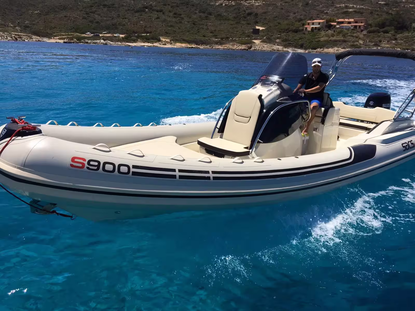 Bateau semi-rigide S900 blanc et moderne naviguant sur l'eau turquoise près de la côte en Haute-Corse.