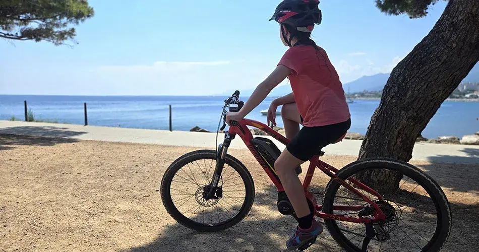 Enfant sur un vélo électrique face à la mer en Haute-Corse