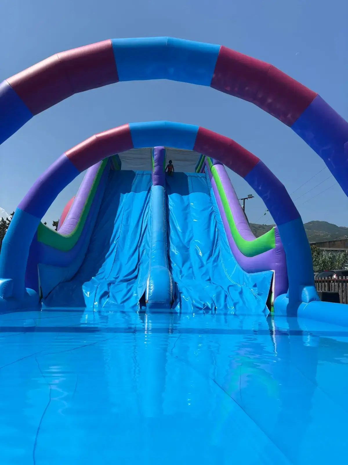 Grand toboggan aquatique gonflable bleu et violet avec arches au Family Parc, aire de jeux aquatique en Corse.