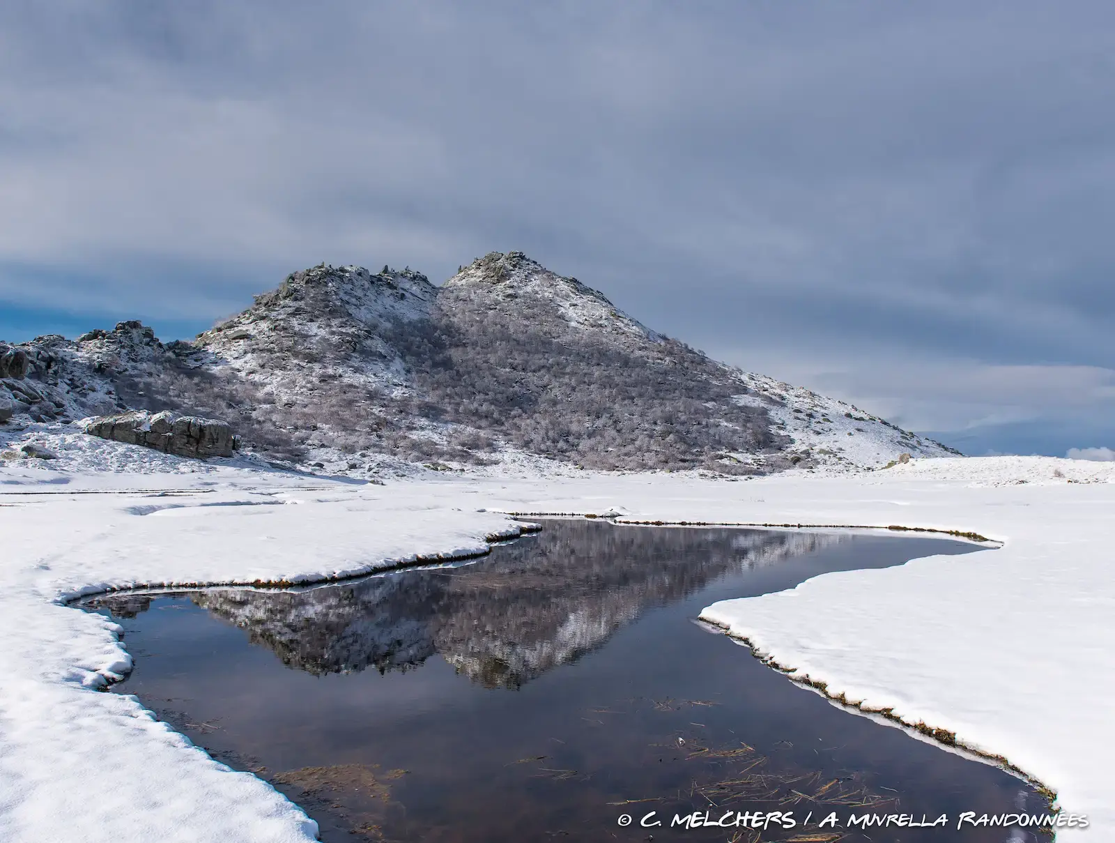 Montagne enneigée se reflétant parfaitement dans la surface plane d'un lac ou d'une mare en hiver.