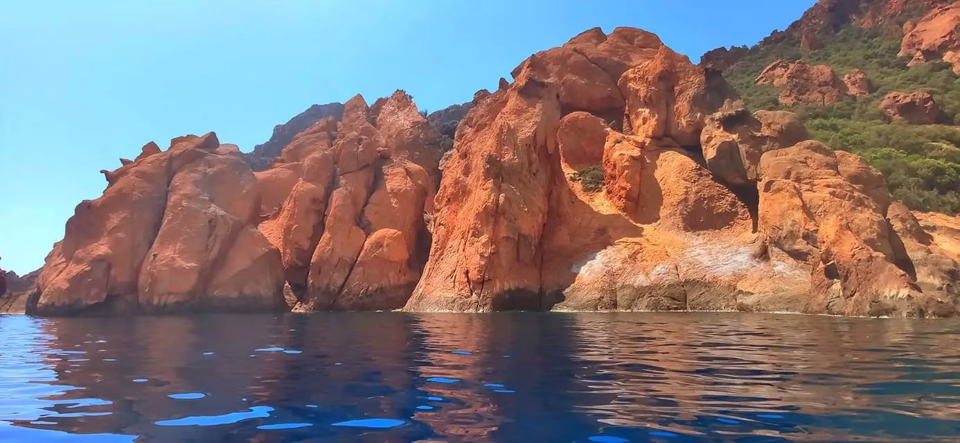 Falaises de granit rouge sculptées par l'érosion formant des arches et des grottes dans la réserve naturelle de Corse.