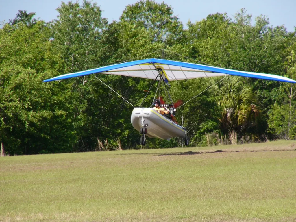 Activités bateau volant : ULM hydro, coque gonflable sous une aile souple bleue et blanche, en vol rasant